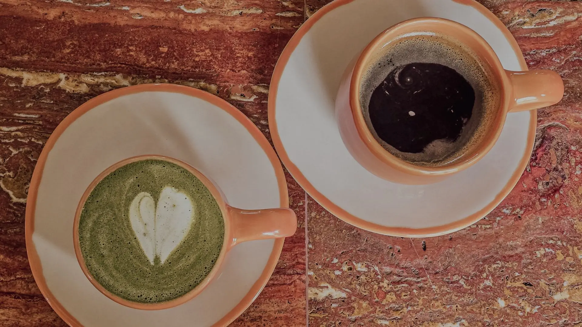 Black coffee and matcha latte with latte art at Carta Ajena restaurant Cartagena