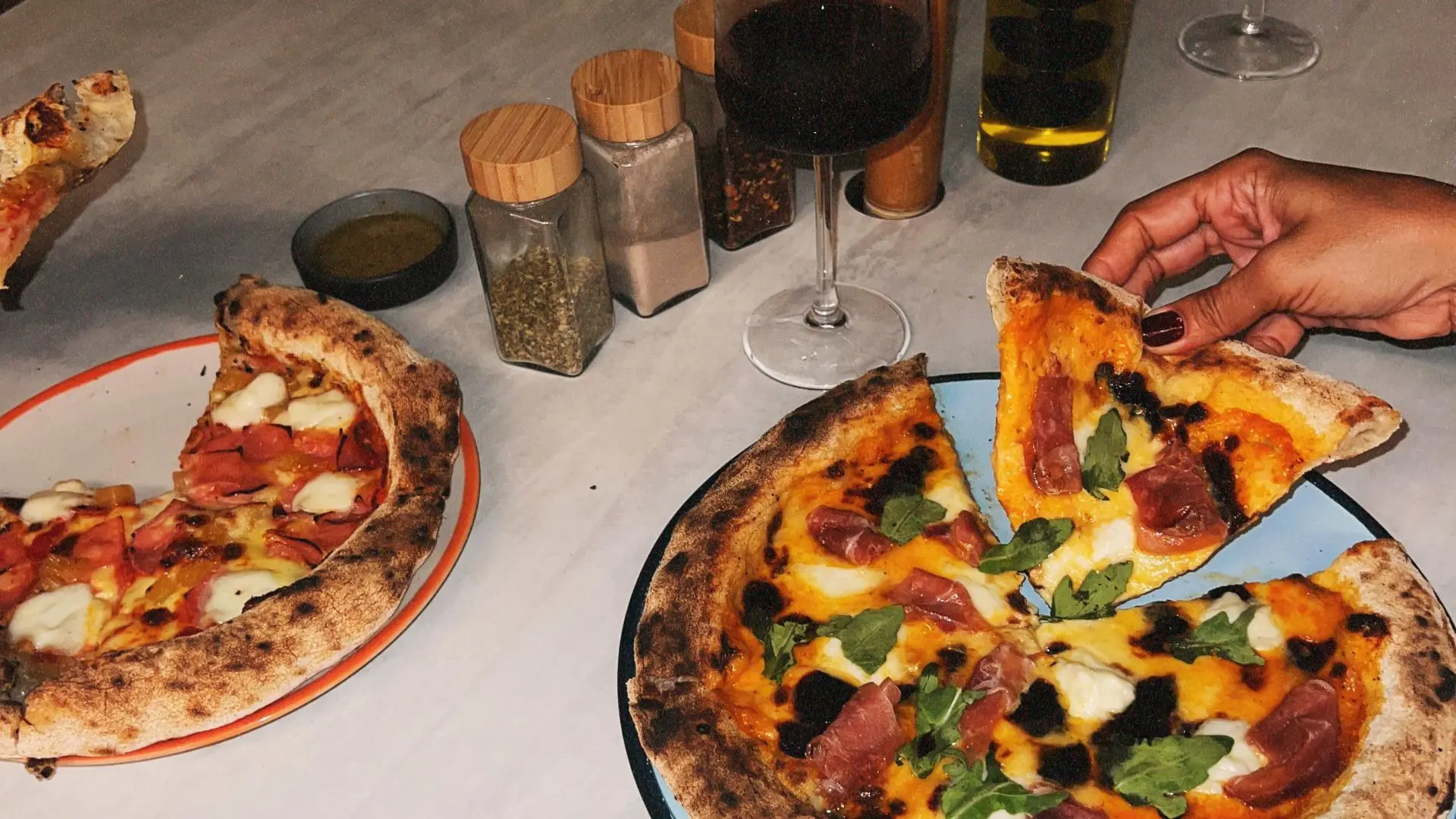 Table with gourmet pizzas and a glass of wine at OSH Hotel Getsemaní restaurant