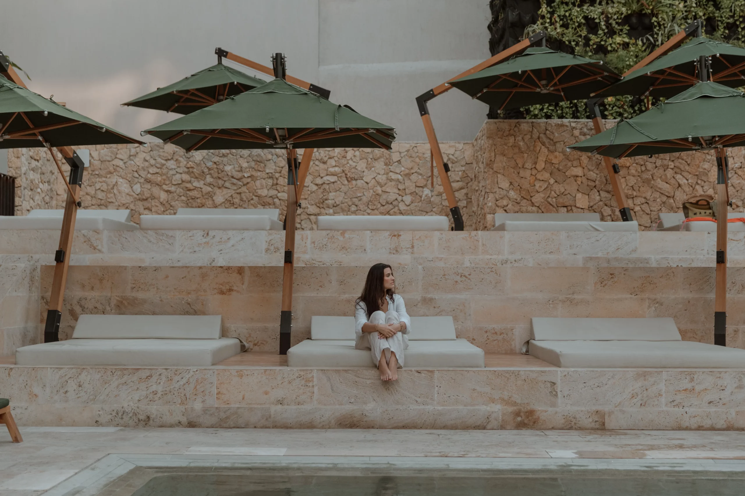 Guest relaxing on tiered sunbeds with green umbrellas in Cartagena