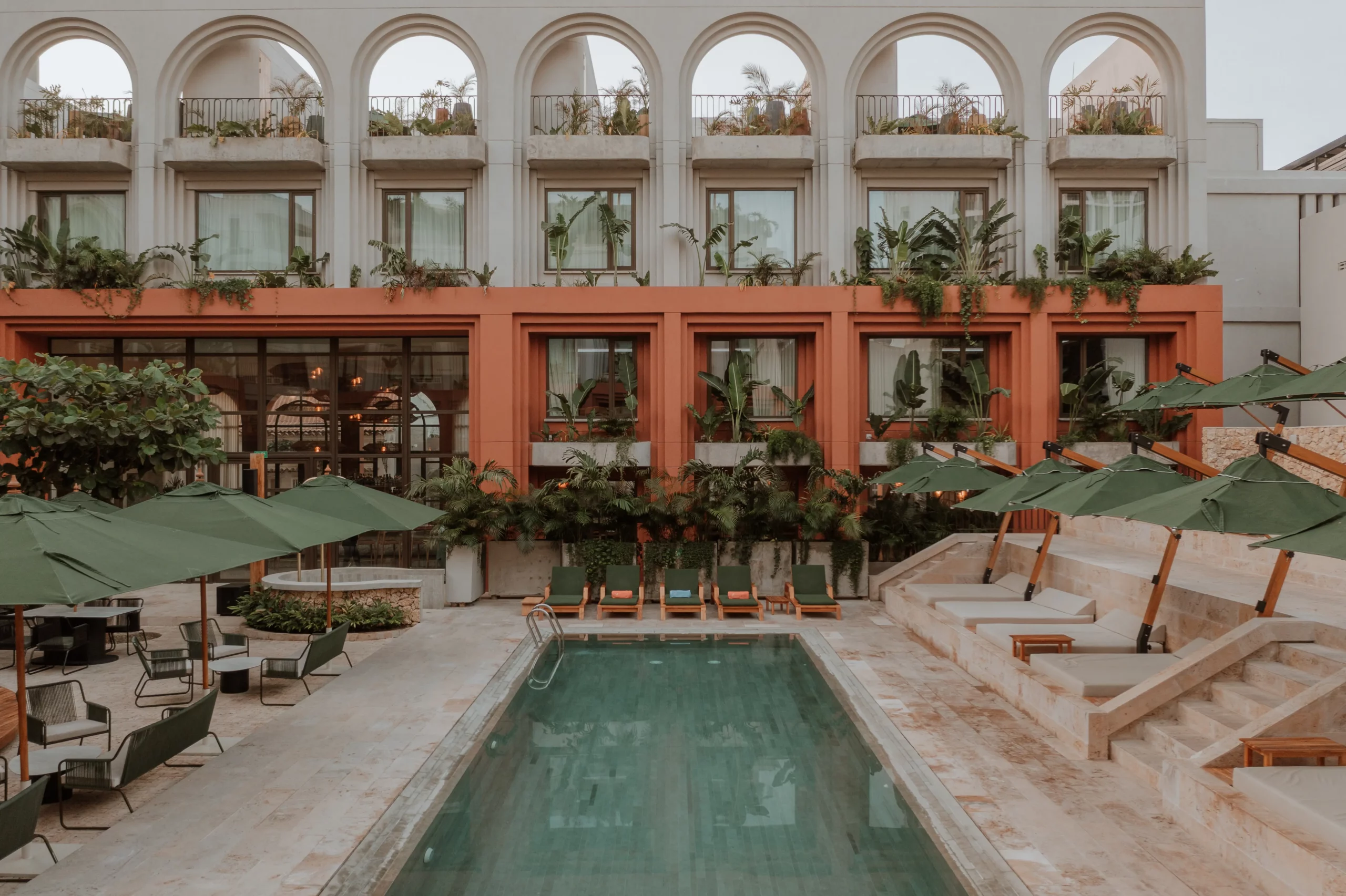 Pool with sunbeds and green umbrellas at hotel in Cartagena