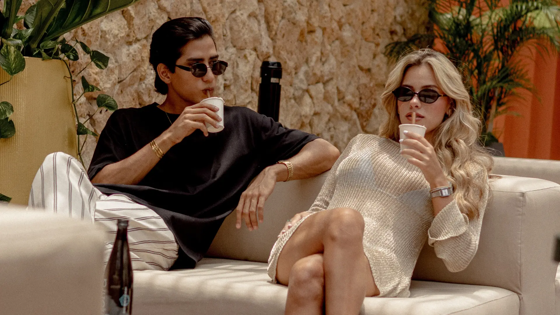 Pareja relajándose en un sofá al aire libre en Cartagena, disfrutando de bebidas con gafas de sol, en un mood slow y sin prisas.