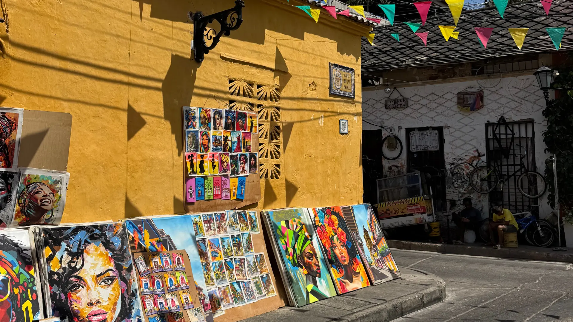 Pinturas en Getsemaní con arte urbano vibrante, retratos coloridos y calles llenas de vida en un día soleado.